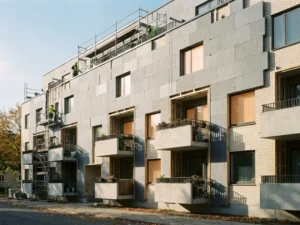 Appartementengebouw met grijze isolatiepanelen op de gevel, balkons zichtbaar achter de thermische bekleding, gefotografeerd van straatniveau.